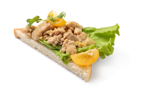 Tasty sandwich with cod liver, lettuce and tomatoes isolated on white background, closeup