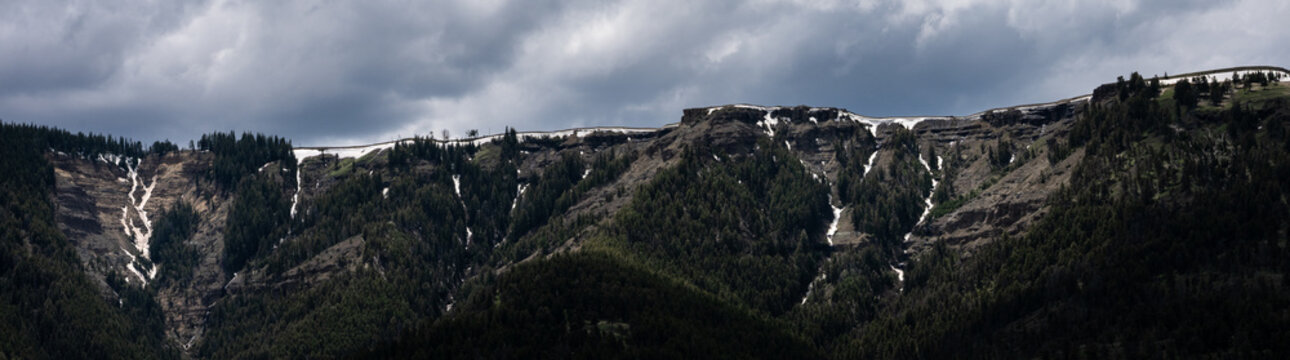 Dramatic landscape in Lamar Valley, cloudy day with sun beams highlighting cliff features, summer vacation in Yellowstone National Park
