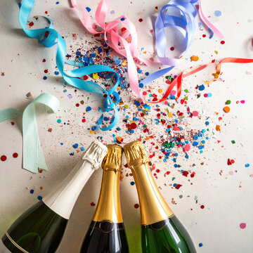 Festive celebration with colorful ribbon, confetti, and sparkling wine bottle arranged on white surface, creating joyful party atmosphere for new year event