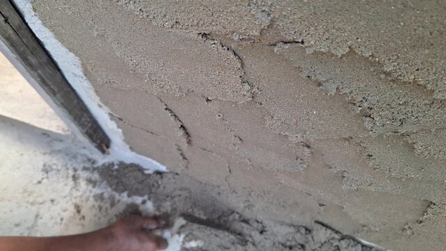 Builder Smoothing and Finishing Concrete Mortar on Wall Surface Using Trowel During Construction and Plastering Work
