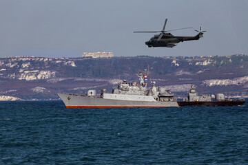 Fototapeta premium A helicopter flies over a warship during a naval exercise in black sea near territorial waters.