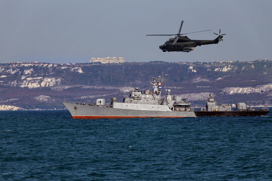 A helicopter flies over a warship during a naval exercise in black sea near territorial waters.