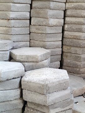 Numerous stacks of octagonal concrete pavers are piled up. The gray blocks show a rough, weathered texture.