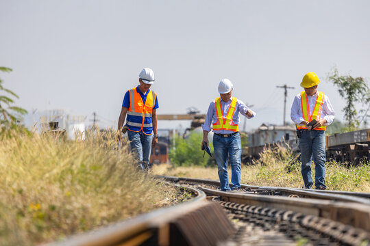 Team of Railway engineers walking and inspecting railway tracks outdoors, Railroad workers in safety gear walking along train tracks, Civil engineers inspecting railway infrastructure and tracks