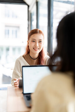 Asian Business Woman Smiling and Holding Stylus Pen During Meeting in Cafe