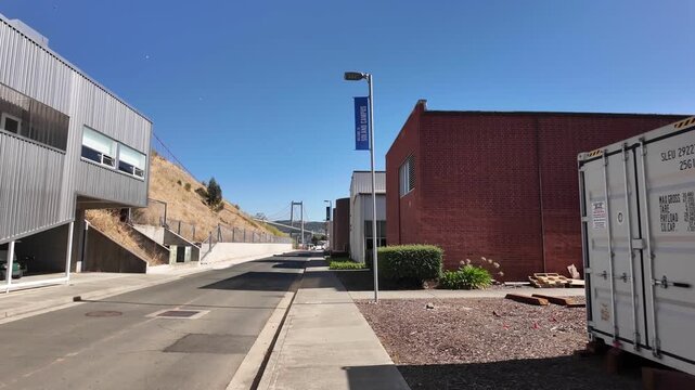 Sunny day view while walking through the California State University Maritime Academy campus in Vallejo, with the Carquinez Bridge visible in the background against a clear blue sky