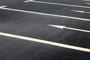 Fototapeta premium Empty outdoor parking spaces with white directional arrows.