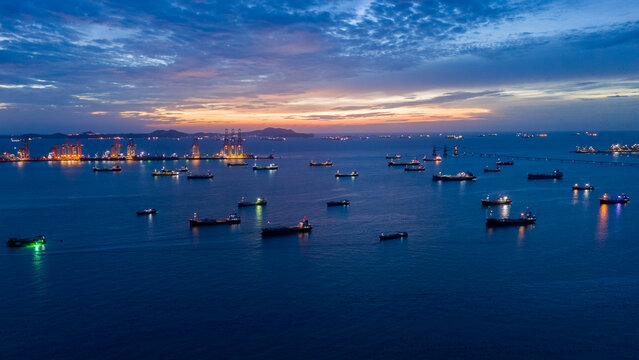 heavy oil tankers and LNG vessels anchored at a strategic maritime chokepoint during a golden sunset, emphasizing global energy crises and petroleum supply chain infrastructure.