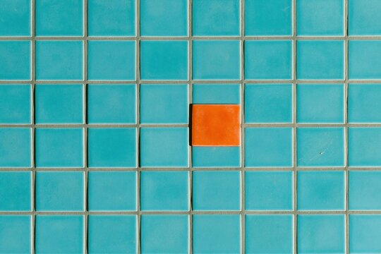 Small square ceramic tiles in bright sky blue with a single orange accent, featuring a glossy glaze and grey grout for a backsplash material backdrop