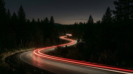 winding road with red light trails at night through forest © Ofida Studio