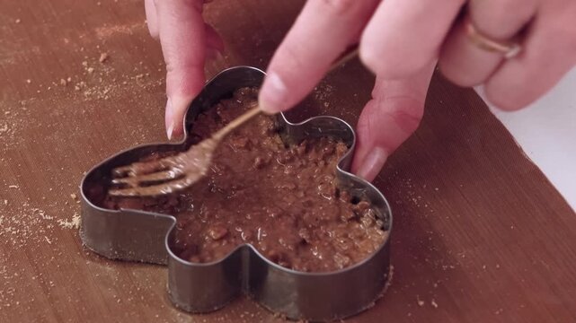 Confectionery recipe. Dessert making. Baker hand spreading brown cream in metal cookie shape preparing gingerbread man caramel top.
