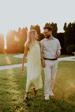 Couple walks hand in hand during sunset in a park setting