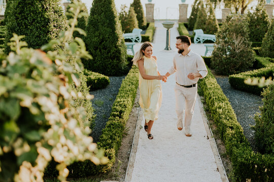 Couple walks hand in hand on a garden path during a sunny afternoon