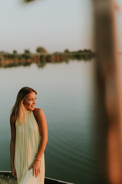 Woman standing by the water at sunset with reflections in the background