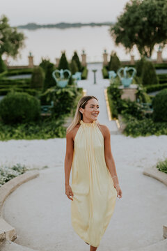 Woman walking in a garden during sunset near a lake with green plants and paths