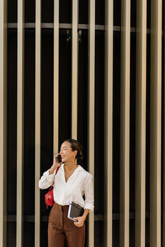 Korean woman enjoys a sunny day while on the phone, radiating joy and style