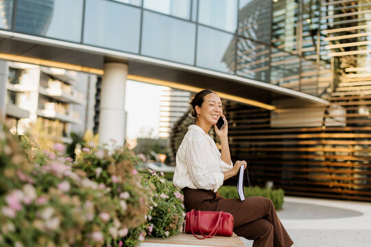 Korean woman enjoying a sunny day while chatting on the phone outdoors