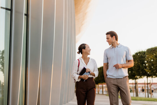 Joyful couple strolls together, sharing laughter in the evening light