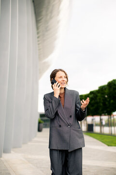 Businesswoman talks on phone near modern building in city