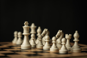 white chess pieces on a wooden board, on black background © geargodz