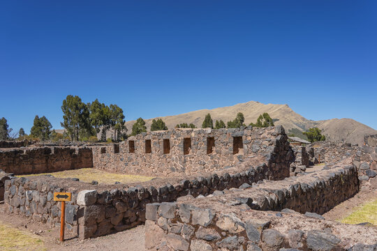 The ruins of the famous ancient Inca temple of Wiracocha Raqchi. Half‑ruined masonry walls, trapezoidal niches. Mountains against a blue sky. Peru. Cusco. Copy space.