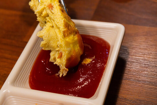 Dipping Savory Korean Rolled Omelet Gyeran Mari into Red Tomato Ketchup