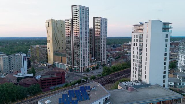 Rooftop solar panels on modern residential buildings, with high rise towers in regenerated town centre, aerial dolly forward