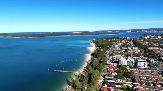 Aerial establishing overview of Ramsgate beach and waterfront along Botany Bay, drone orbit of suburb and buoys surrounding beach