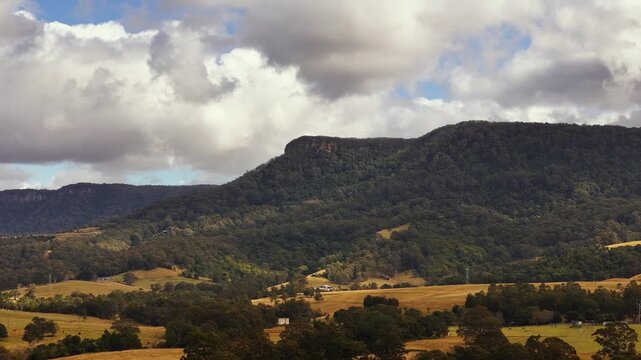 Illawarra Escarpment rising above rolling farmland beneath dramatic clouds, aerial medium backdrop