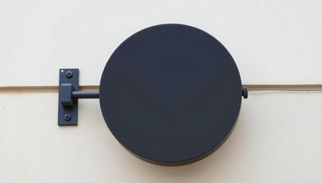 Empty round black hanging sign mounted on a building wall