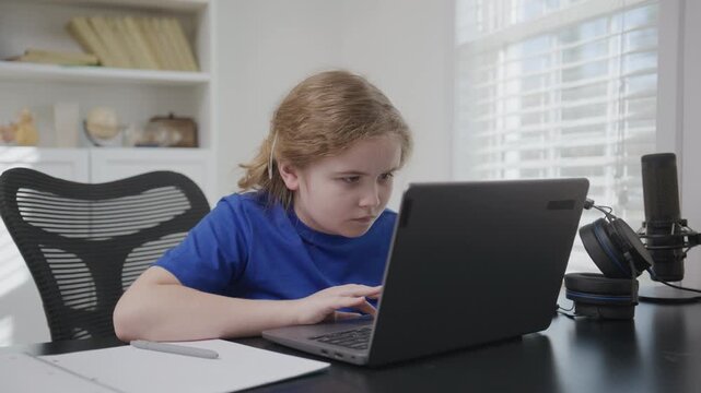 School kid study online. Child studying on laptop desk. Child watching lessons on laptop. Child concentrating during laptop work. Child doing homework on laptop.