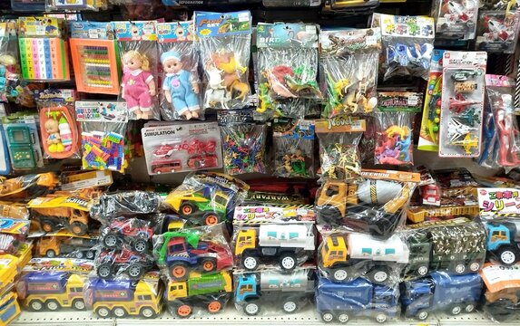 KUALA TERENGGANU, MALAYSIA- AUGUST 20. 2026: Retail display filled with hanging and stacked plastic packaged toys, construction trucks, and figurines for stock photography metadata.