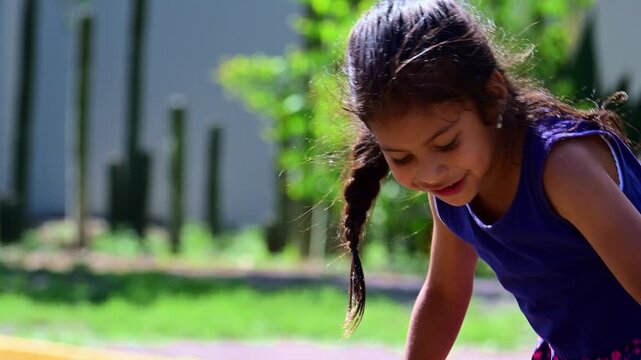 Latina girl holding herself up with her arms on playground equipment