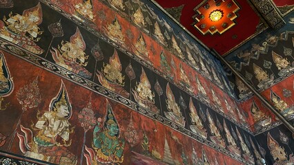 Traditional Thai Buddhist mural painting depicting Buddhist mythology on the temple wall in Bangkok, Thailand. © lawplow