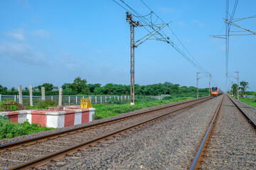 Fototapeta premium Saffron coloured Vande Bharat Express near Pune India. This is a made in India train set and also known as Train 18.