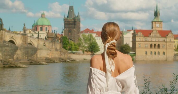 Woman tourist looking at Charles Bridge and Vltava River cityscape on a sunny day in Prague city