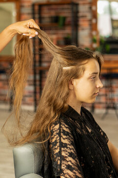 Hairstylist Lifting Long Hair Section of Teen Client