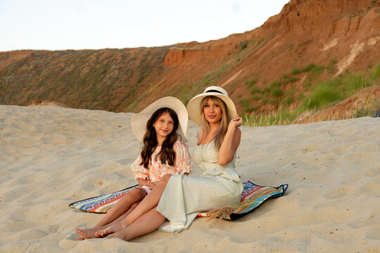 Mother And Daughter Posing In Hats On Sand