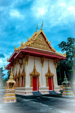 Beautiful Thai temple ordination hall under dramatic blue sky