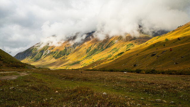 Landscape photograph of golden autumn mountain valley with low clouds in Svaneti Georgia.