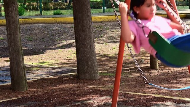 Mexican girl swinging fast in the park