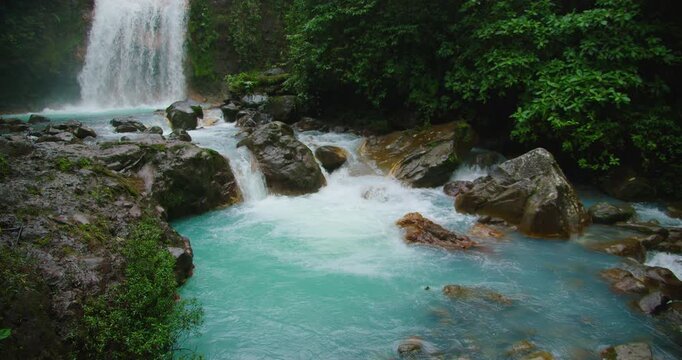 Bright turquoise river and waterfall in Costa Rica rainforest viewed during adventurous travel