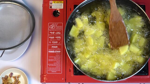 Deep Frying Diced Potatoes in Hot Boiling Oil on Portable Gas Stove