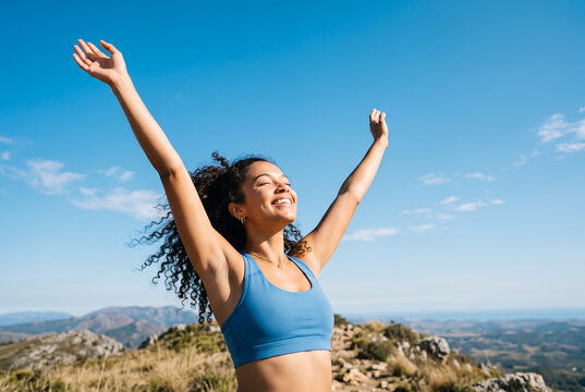 Woman with arms raised celebrating at mountain overlook outdoors