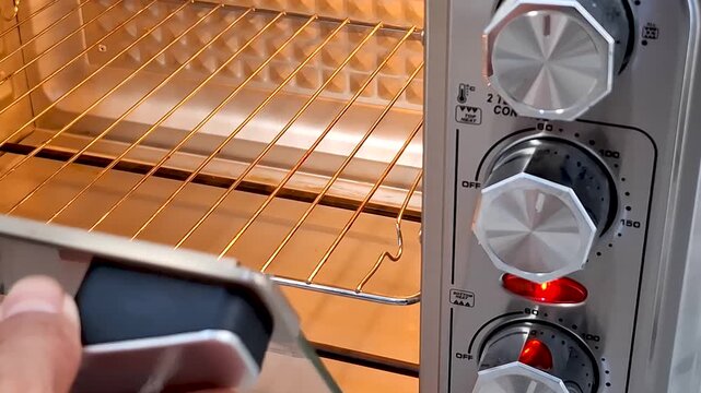 Close up shows a hand inserting a rack into a lit toaster oven with temperature and function controls visible
