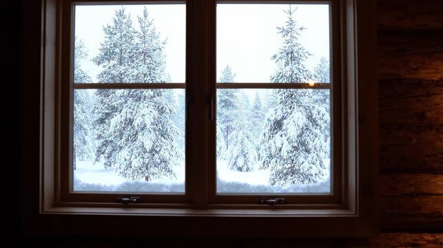 A tranquil winter scene viewed from a warm interior, featuring a snowy forest and gently falling snow.