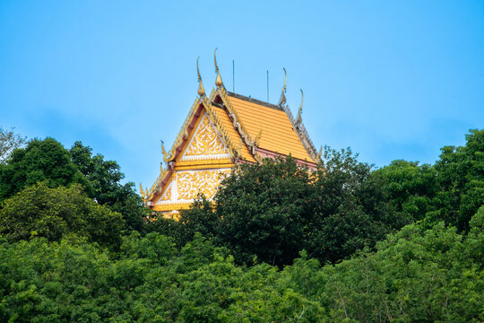 Beautiful golden Thai temple roof peeking out from dense green trees