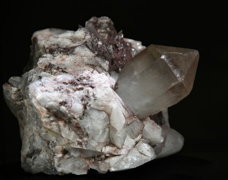 A macro close-up view of a quartz specimen featuring a prominent, well-formed smoky quartz crystal protruding from a light-colored matrix of quartz and feldspar against a dark background.