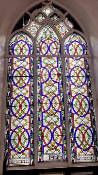 4K footage of colorful stained glass church window with memorial plaques on old wall, showcasing Christian architecture, sacred heritage, religious art and peaceful worship atmosphere.