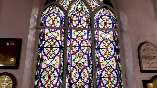4K footage of colorful stained glass church window with memorial plaques on old wall, showcasing Christian architecture, sacred heritage, religious art and peaceful worship atmosphere.